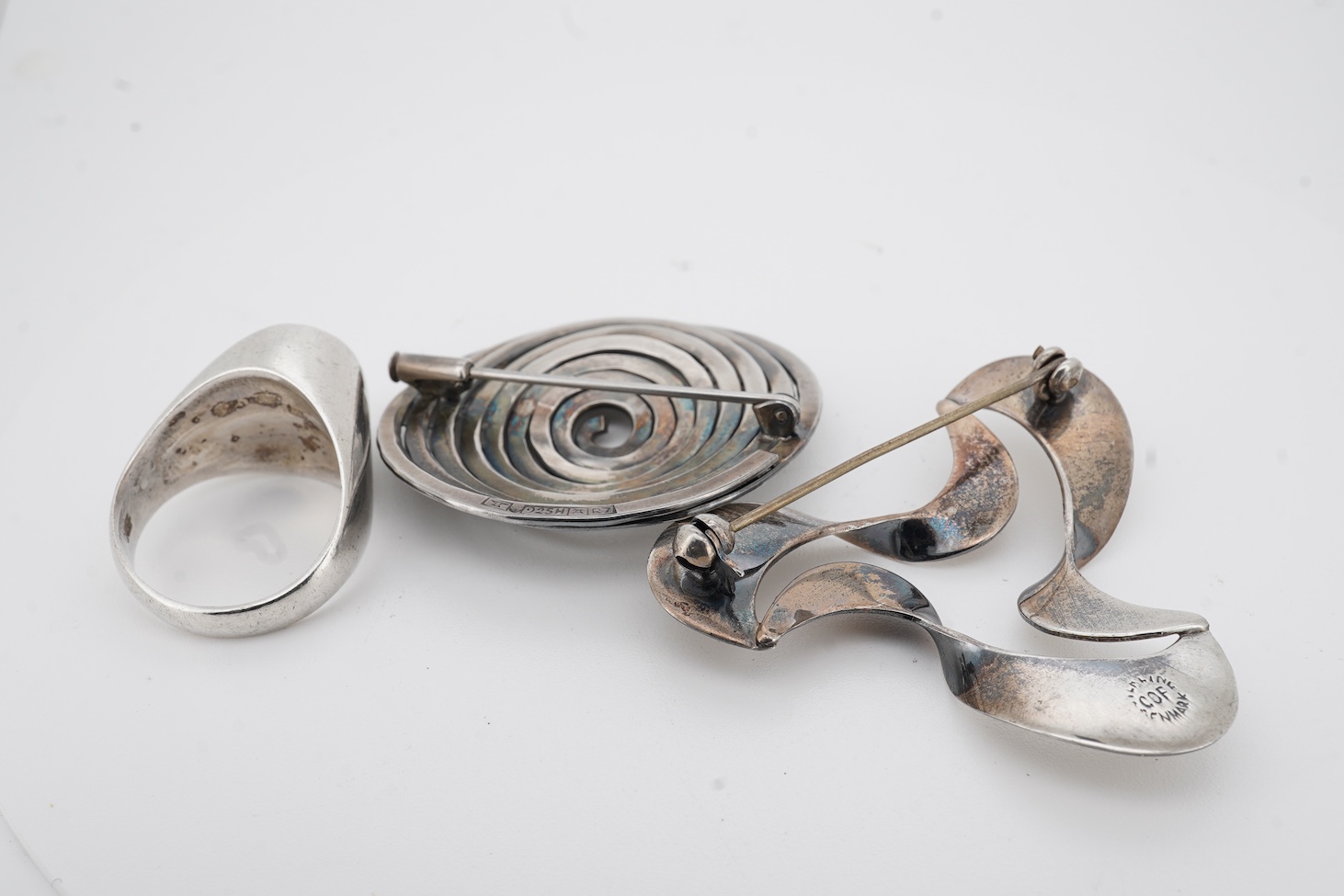 A mid to late 20th century Danish sterling tri-form brooch and a 925S ring by by Carl Ove Frydensberg, brooch, 43mm and a 1970's Finnish 925 circular brooch, by Kuppittaan Kulta, Turku, diameter 36mm.